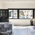 Bright modern kitchen with black cabinets, white island, and large windows overlooking trees.