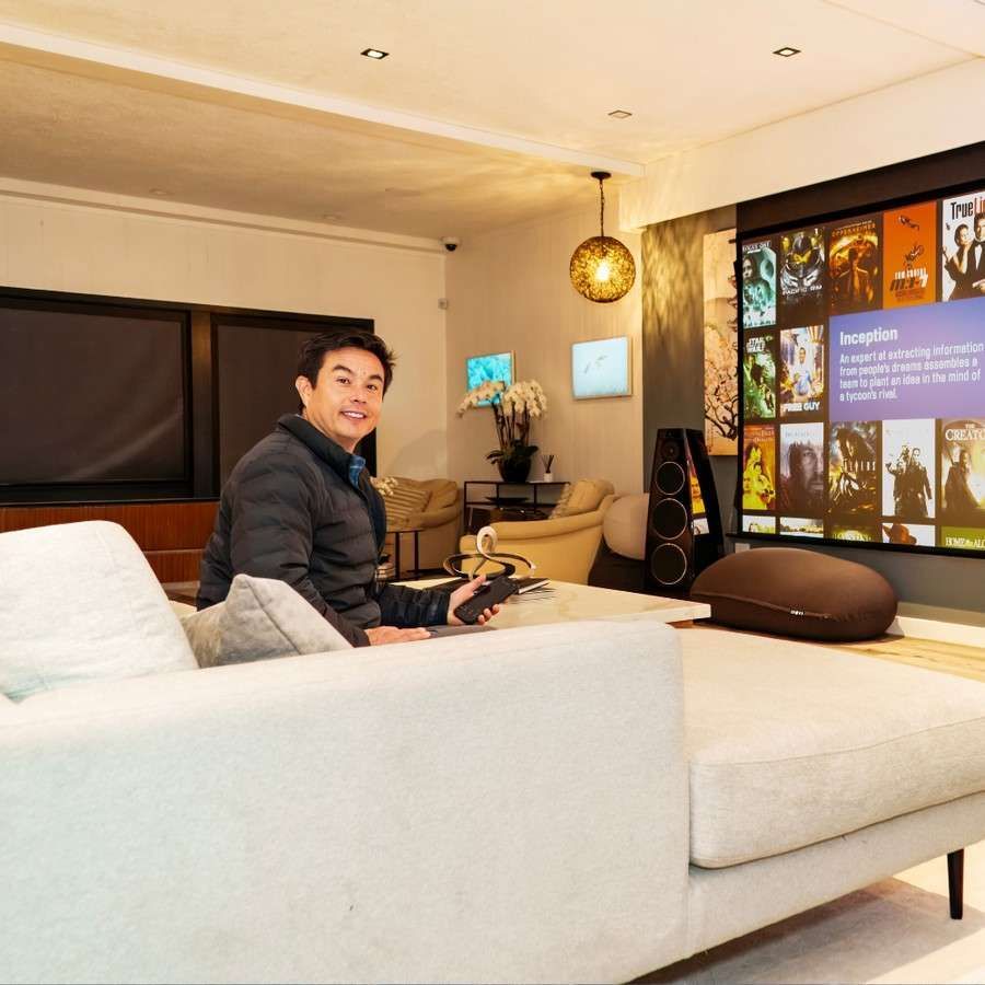 Person sitting on a white sofa in a modern living room with a large wall display and warm lighting