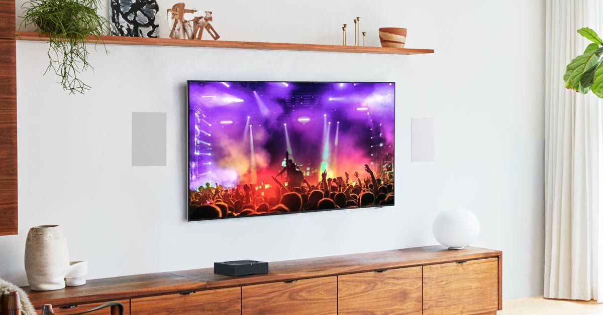 Wall-mounted TV showing a colorful concert scene above a wooden console in a bright living room