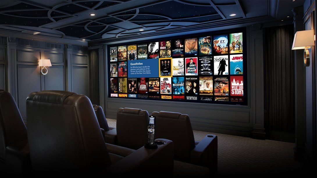 Dim home theater with leather recliners facing a wall of colorful movie posters on a large screen