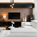 Modern living room with white sectional, wood-paneled TV wall, pendant lights, and decorative vases