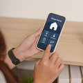 Person using a smartphone app to control a smart home device on a wooden table