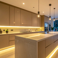 Modern minimalist kitchen with warm under-cabinet and island lighting, beige cabinets, and a long central island