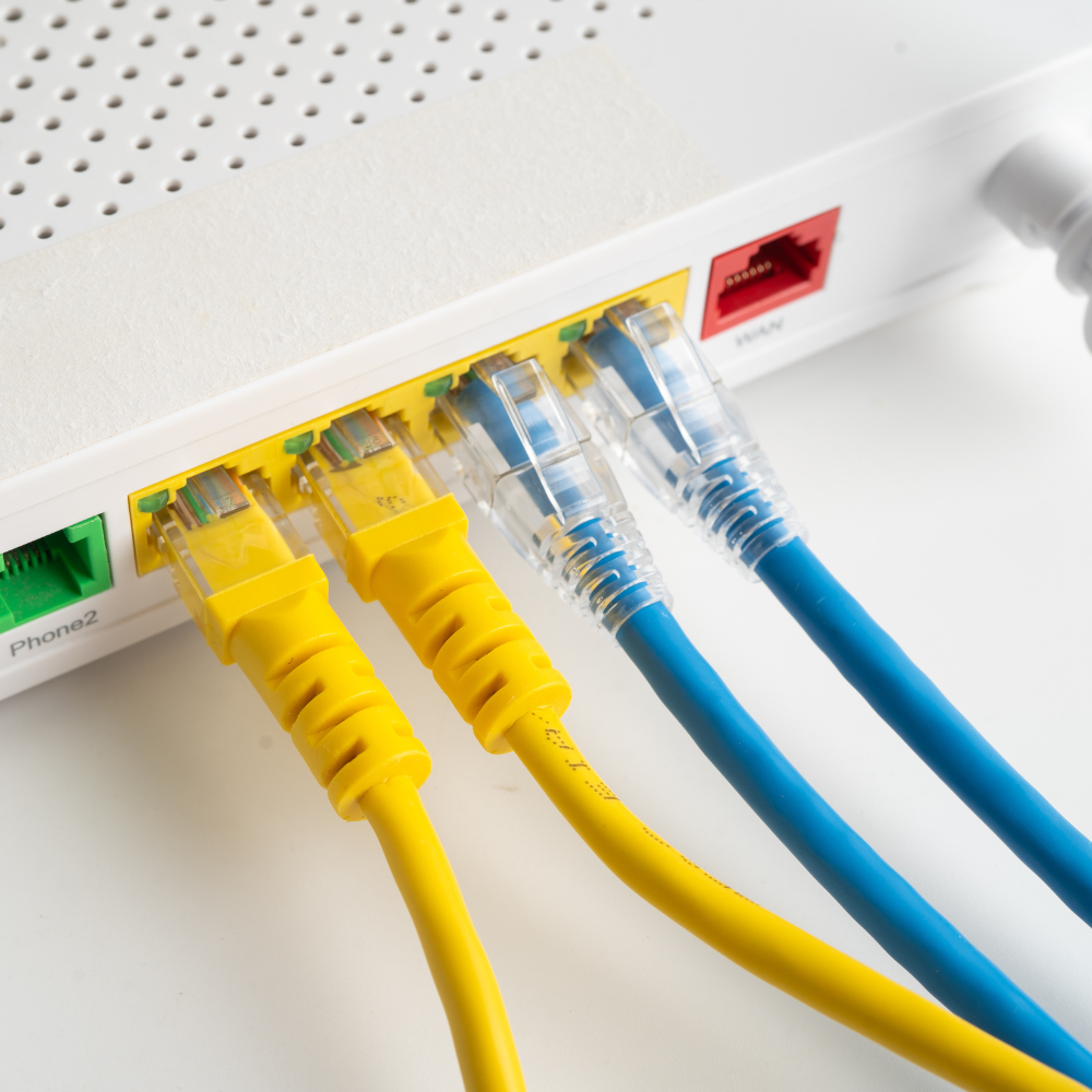 Yellow and blue Ethernet cables plugged into a white network router.