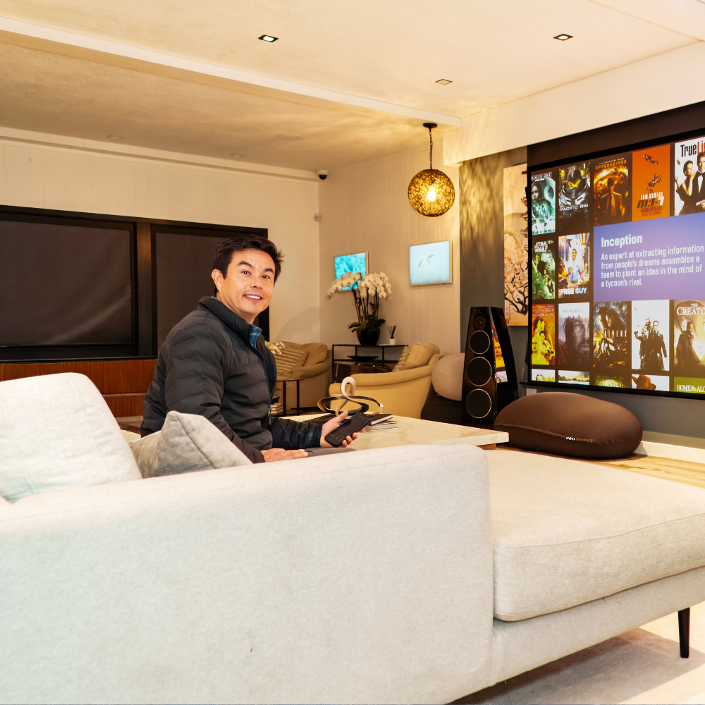 Person sitting on a white sofa in a modern living room with a large wall display and warm lighting