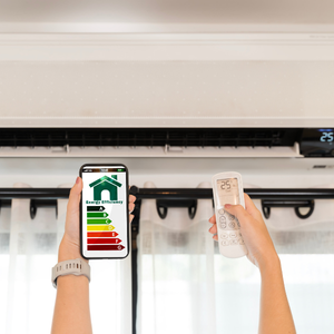 Hands holding a phone and AC remote near a wall-mounted air conditioner with an energy rating label