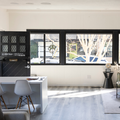 Bright modern kitchen with black cabinets, white island, and large windows overlooking trees.