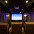 Home theater with recliner seats, dim ceiling lights, and a large projection screen.
