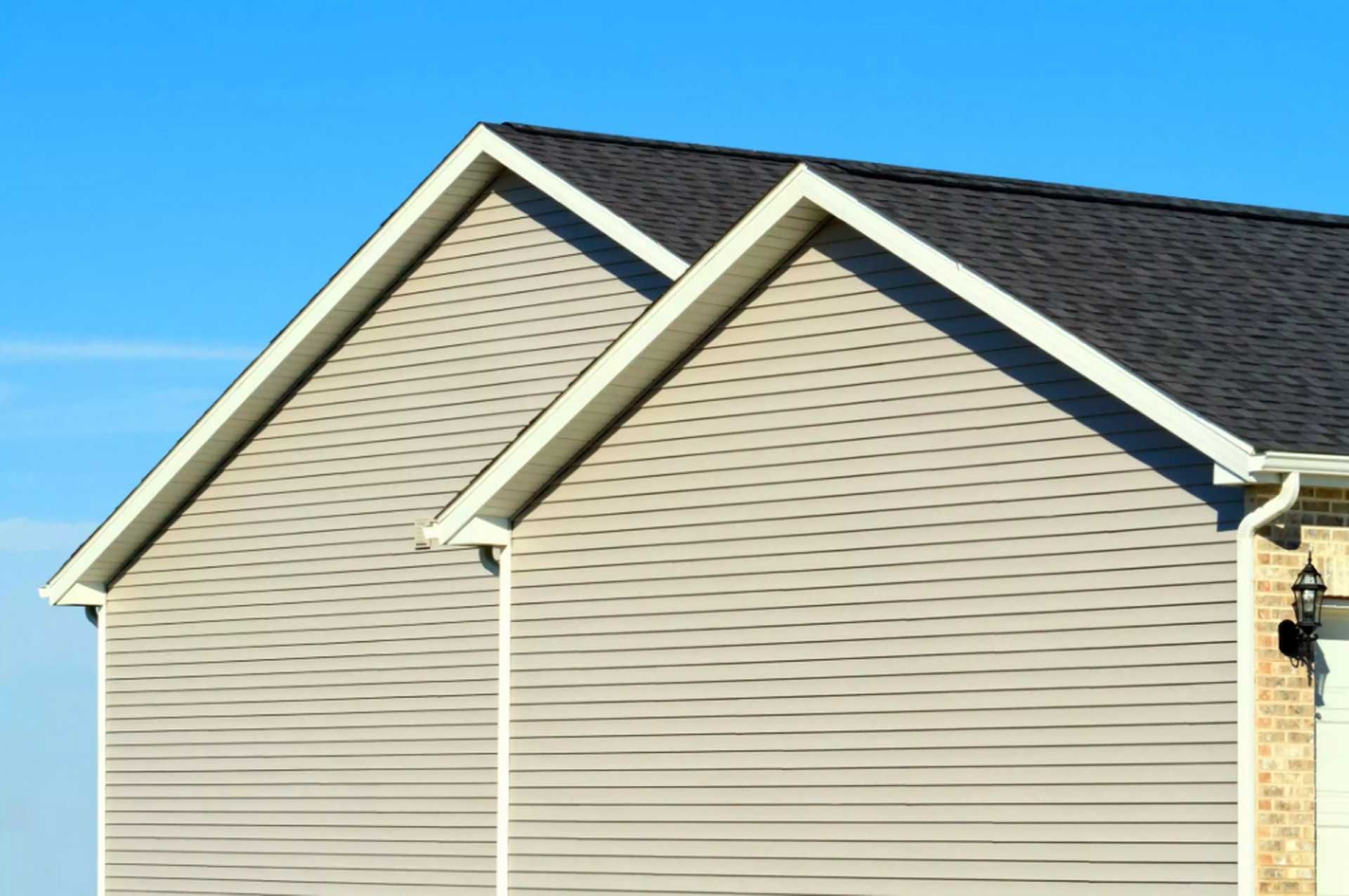 Two beige vinyl-sided gables with a dark shingled roof on a home in Huntsville, AL by LJ Roofing