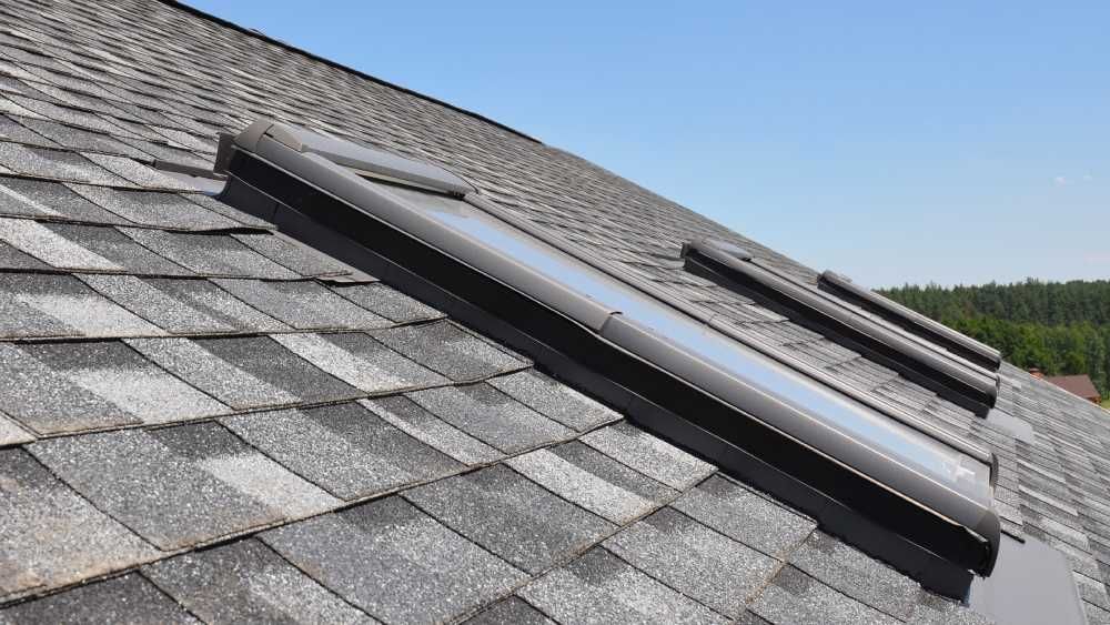 Two dark-framed skylights installed on a sloped roof covered in grey asphalt shingles  in Huntsville AL by LJ Roofing