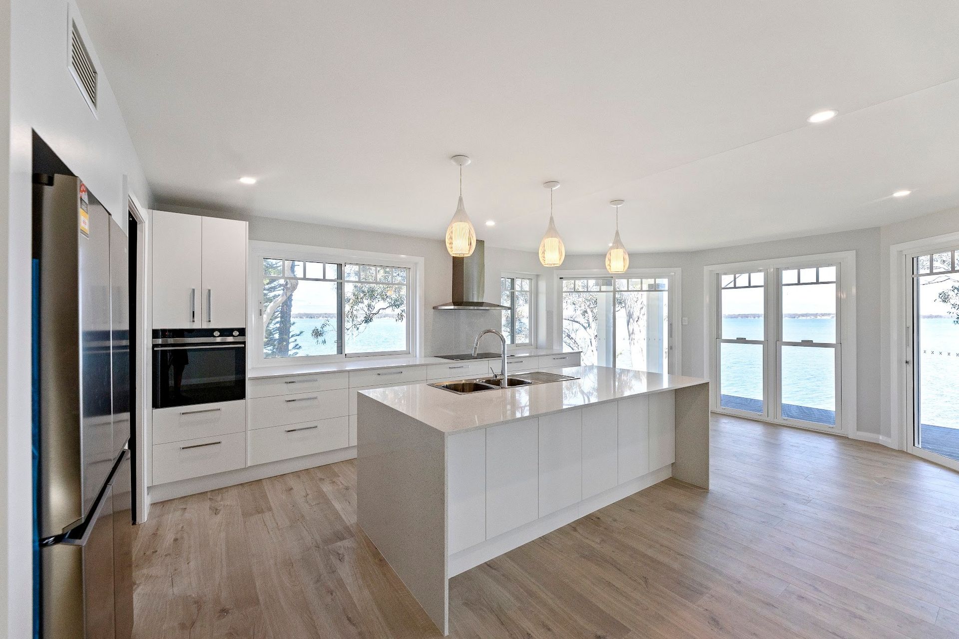 Modern White Kitchen With Island, Wooden Floors, and Water View — Trim Joinery In Hunter Valley, NSW