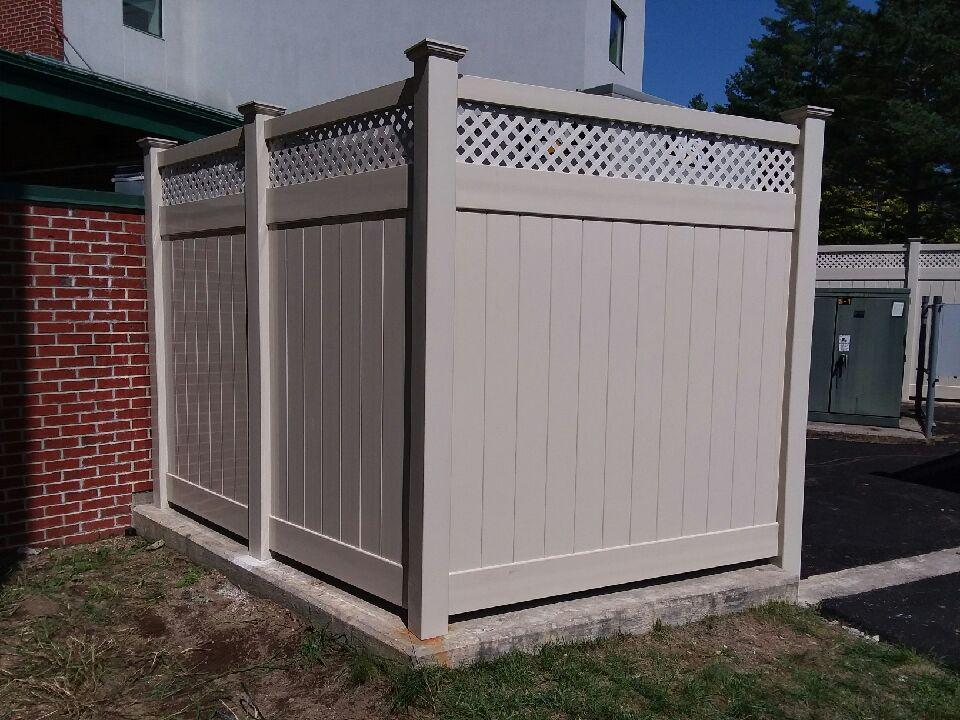 a white fence is sitting in front of a brick building .
