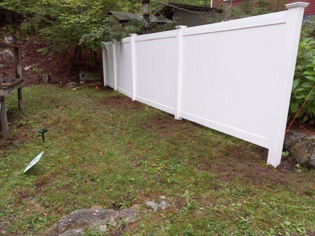 a white fence is sitting in the middle of a lush green yard .