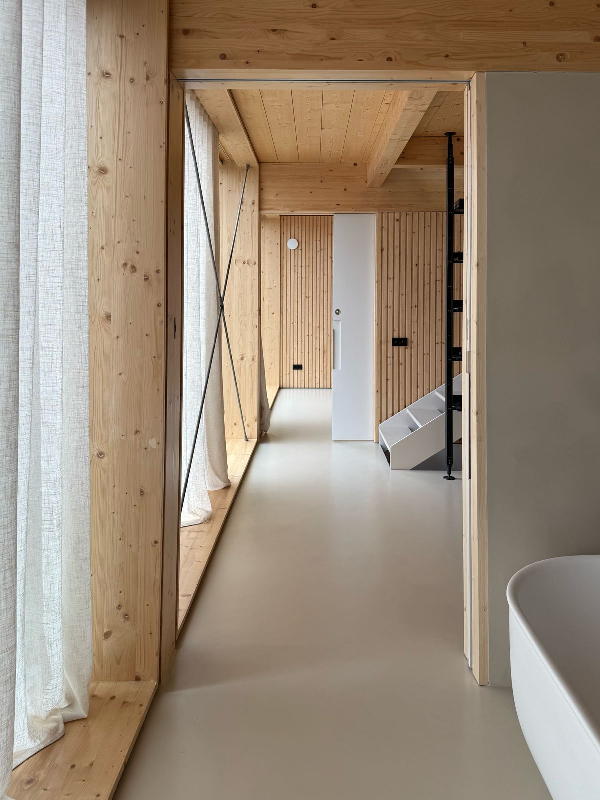 Passadís modern de fusta amb terres clars, grans finestres i disseny interior minimalista