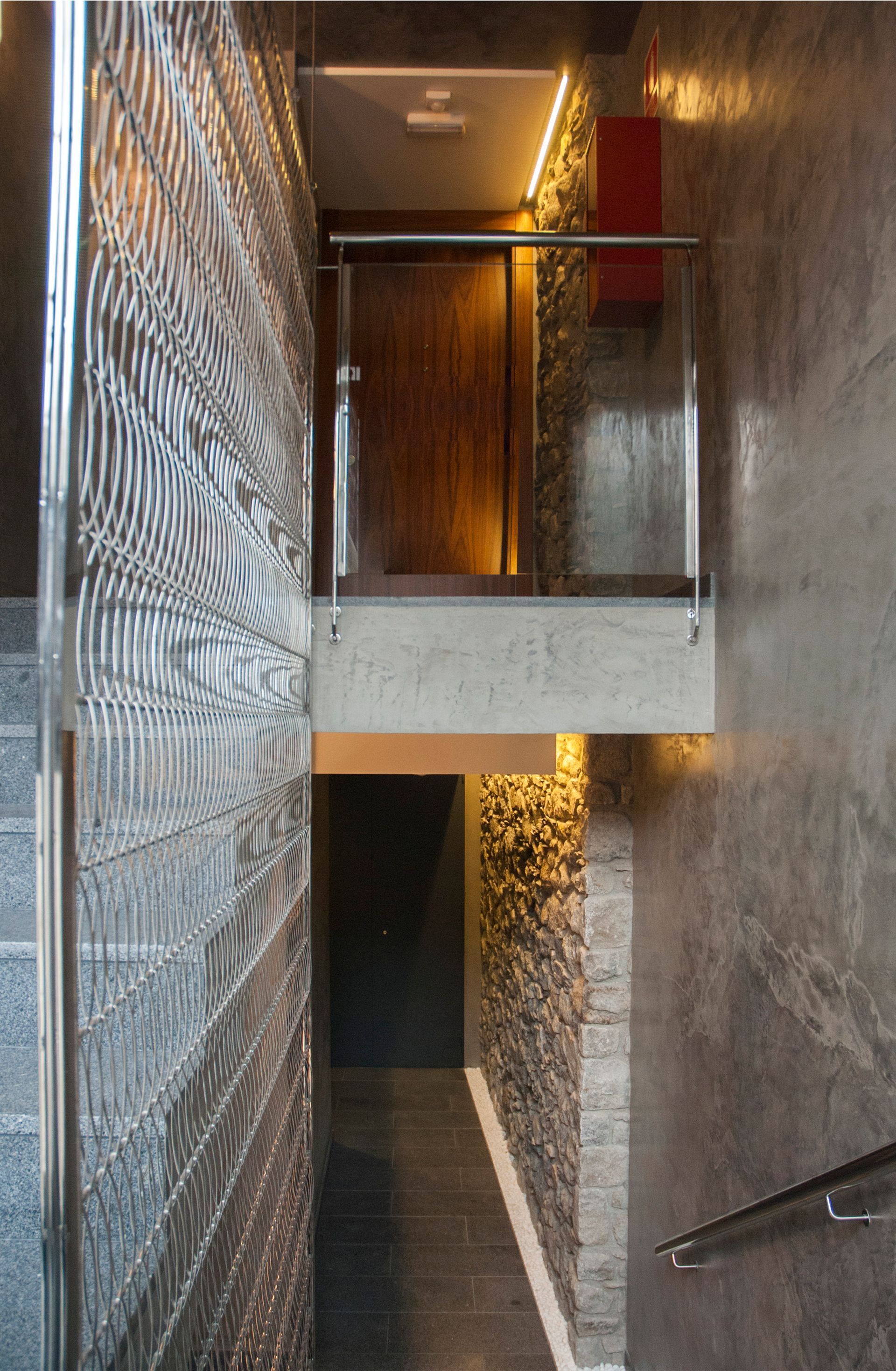 Escala moderna i estreta amb la paret esquerra estampada, la paret dreta de pedra i una il·luminació càlida.