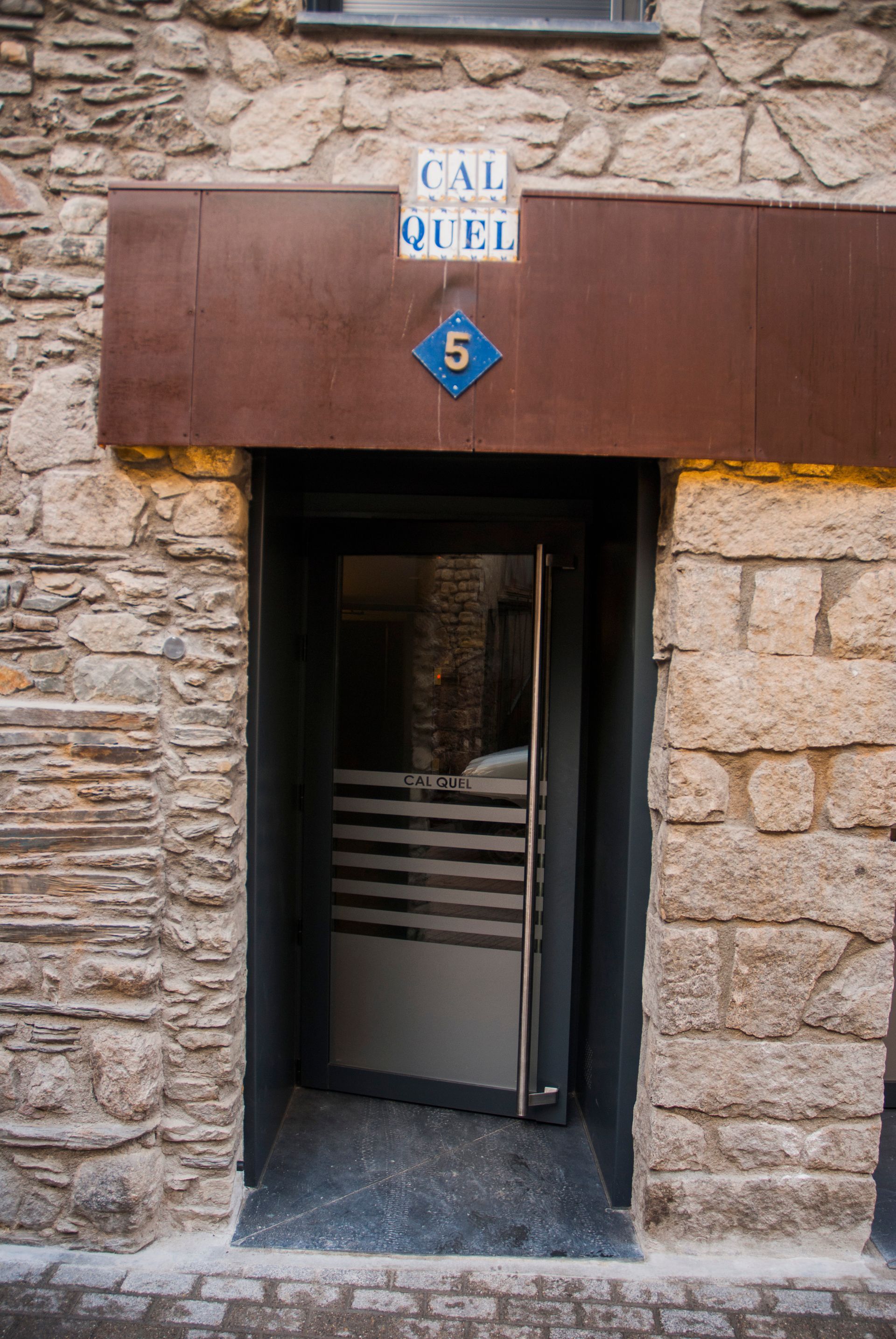 Entrada de pedra amb un tendal marró i un rètol blau amb el número 5 a sobre de la porta.