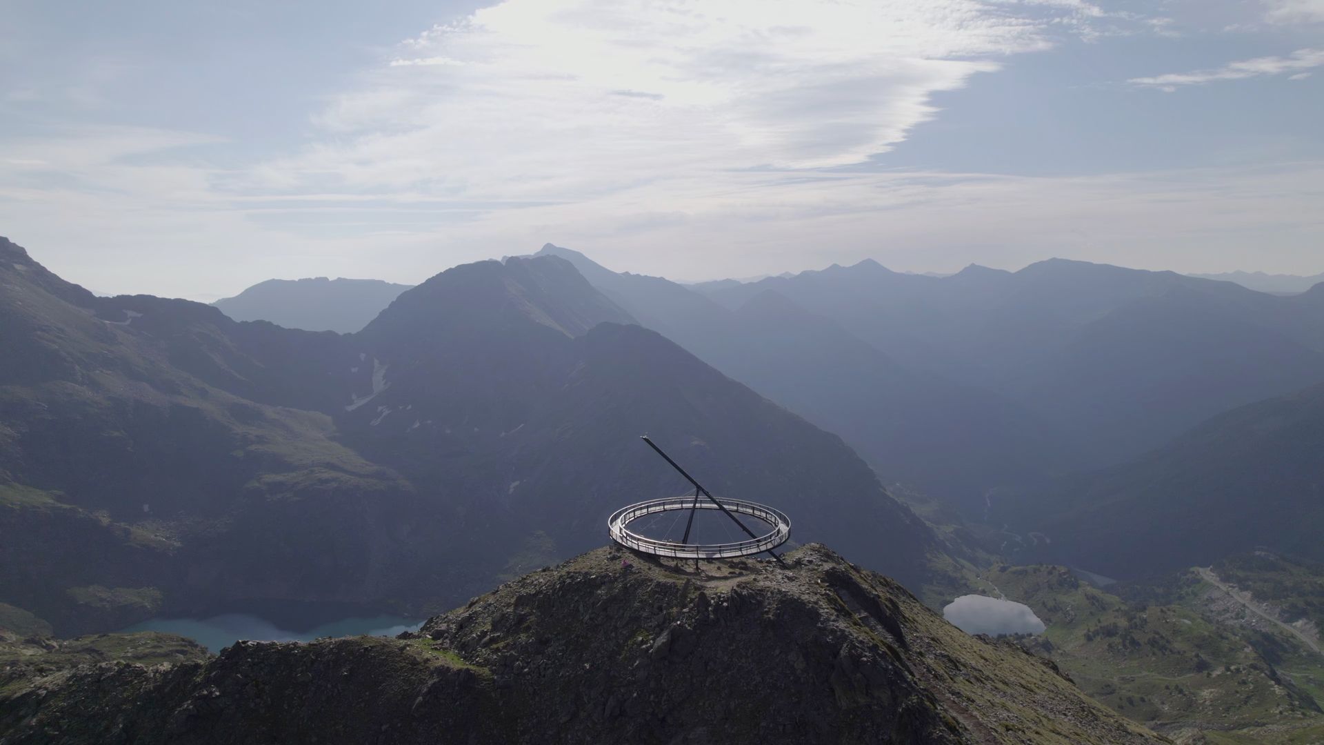 Cim de muntanya amb un petit plat d'observatori amb vistes a les valls estratificades a l'alba