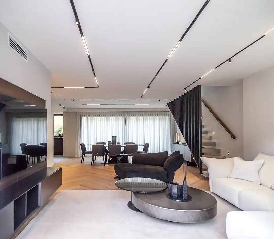 Sala d'estar moderna amb sofà blanc, taula de centre rodona i menjador al darrere