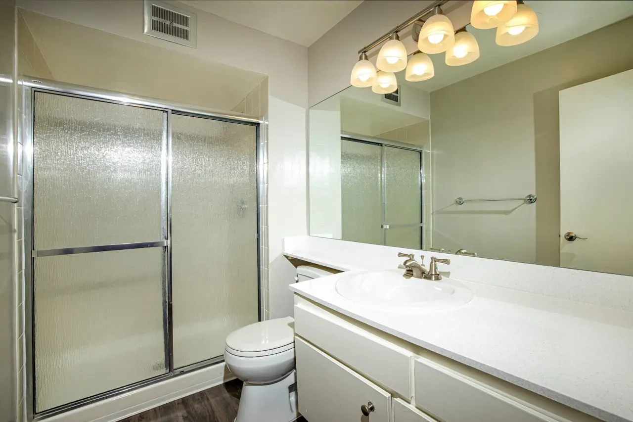 Clean bathroom with a glass shower, toilet, and vanity with a sink.