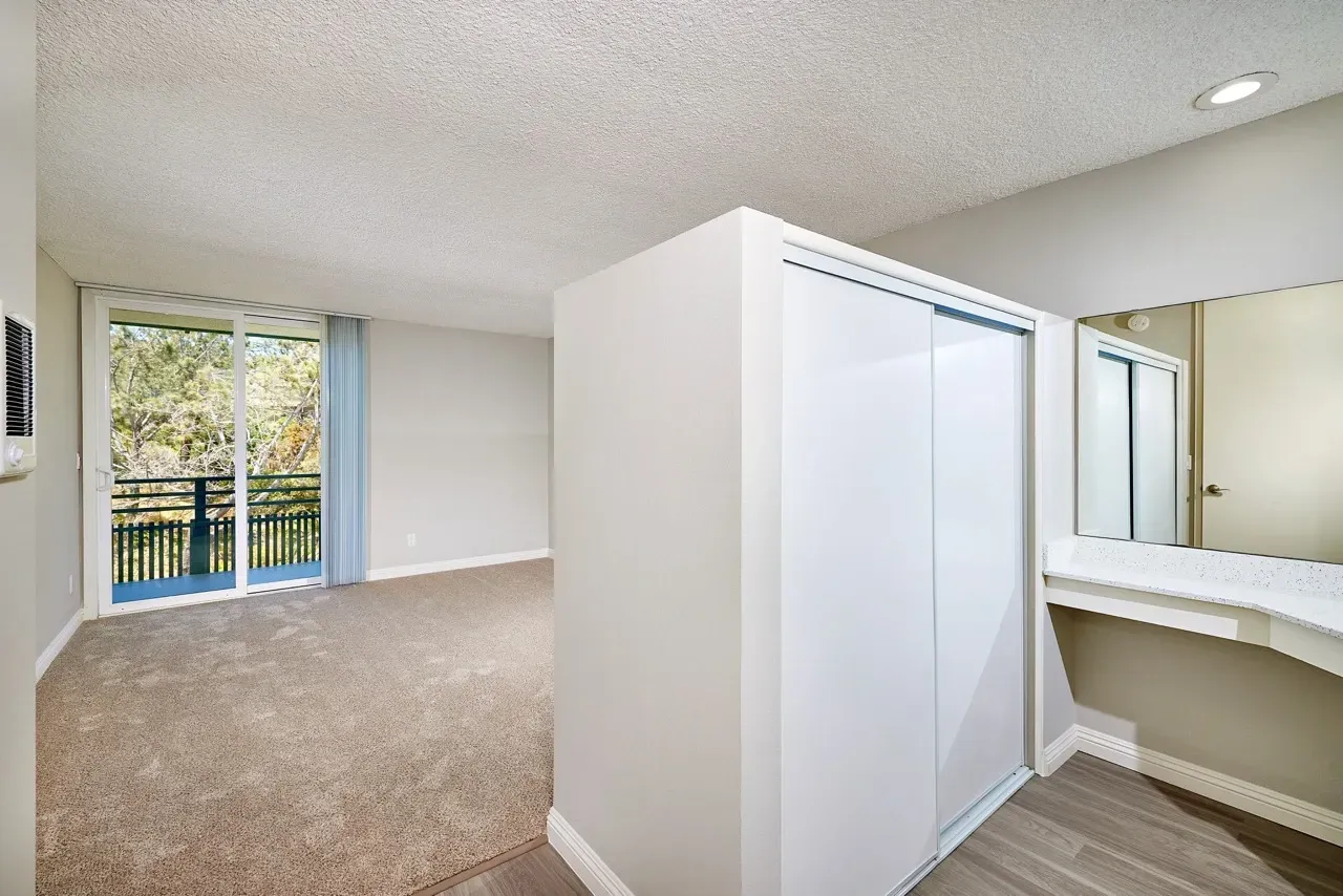 Bedroom with a large closet and vanity area, leading to a balcony.