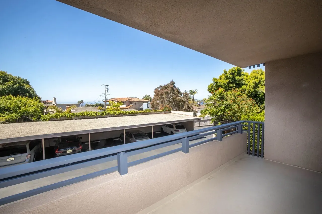 View from balcony overlooking covered parking and distant ocean