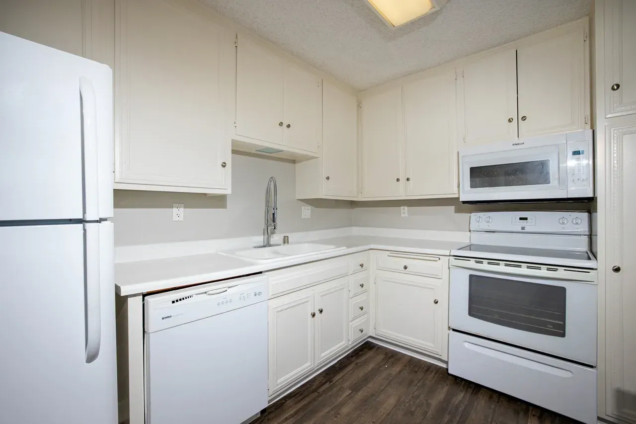 Kitchen with white cabinets, countertops, refrigerator, dishwasher, stove, and microwave.