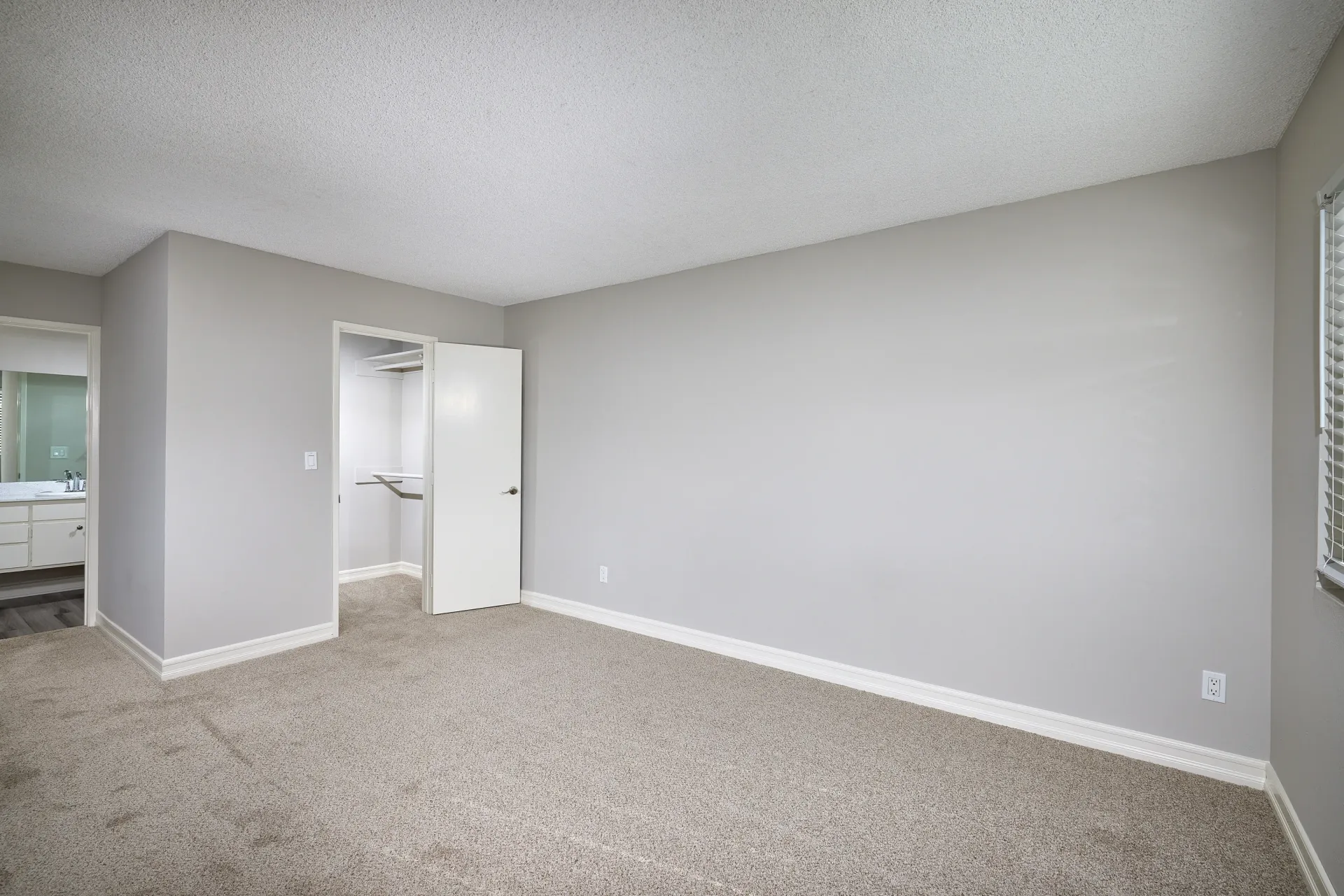 Empty bedroom with a closet and an attached bathroom.