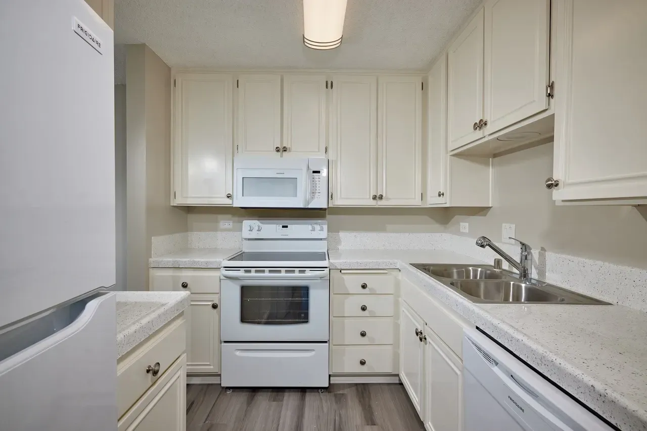 Modern kitchen with white cabinets, stainless steel sink, and white appliances.