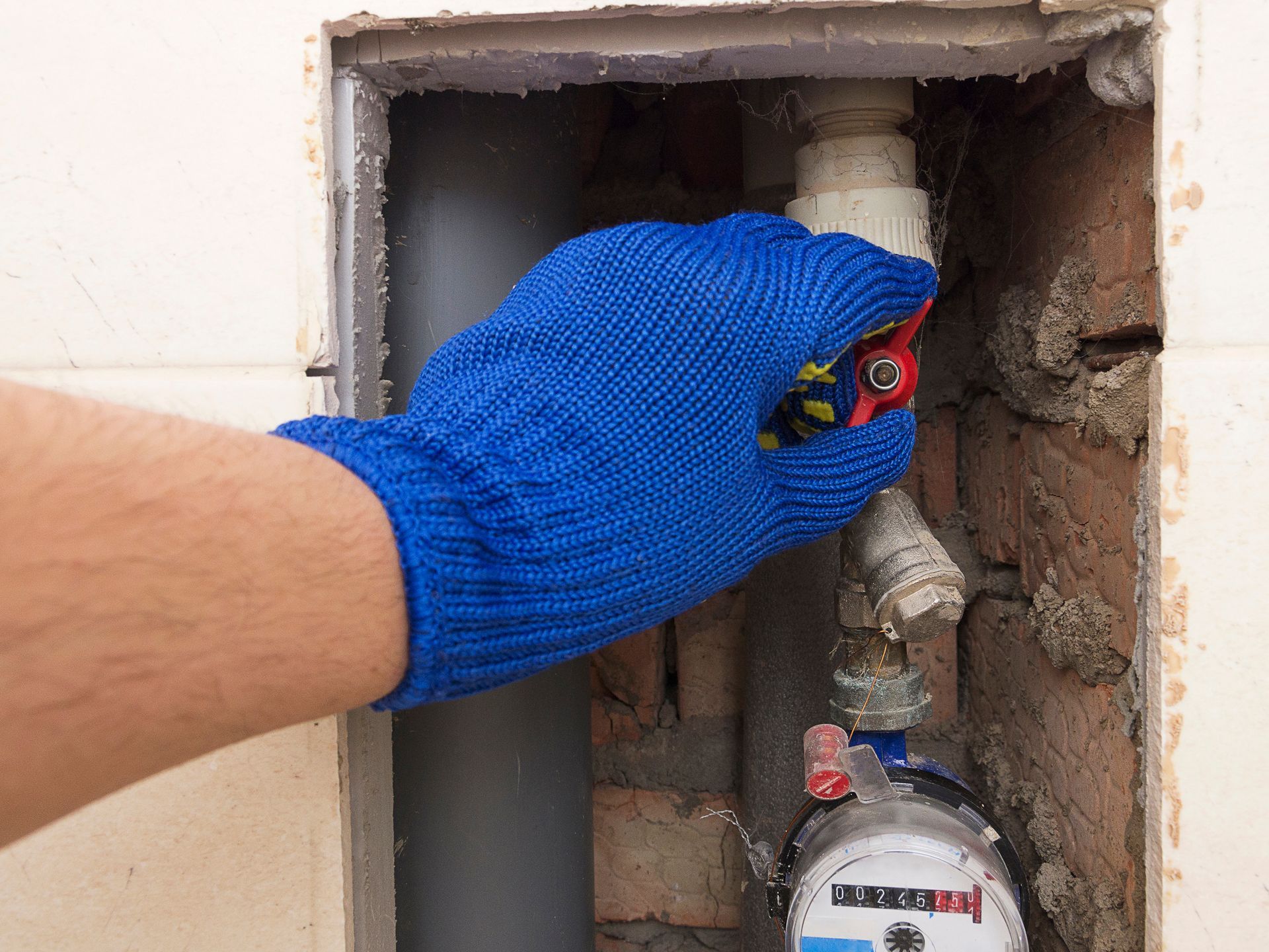 A person wearing blue gloves is fixing a water meter.