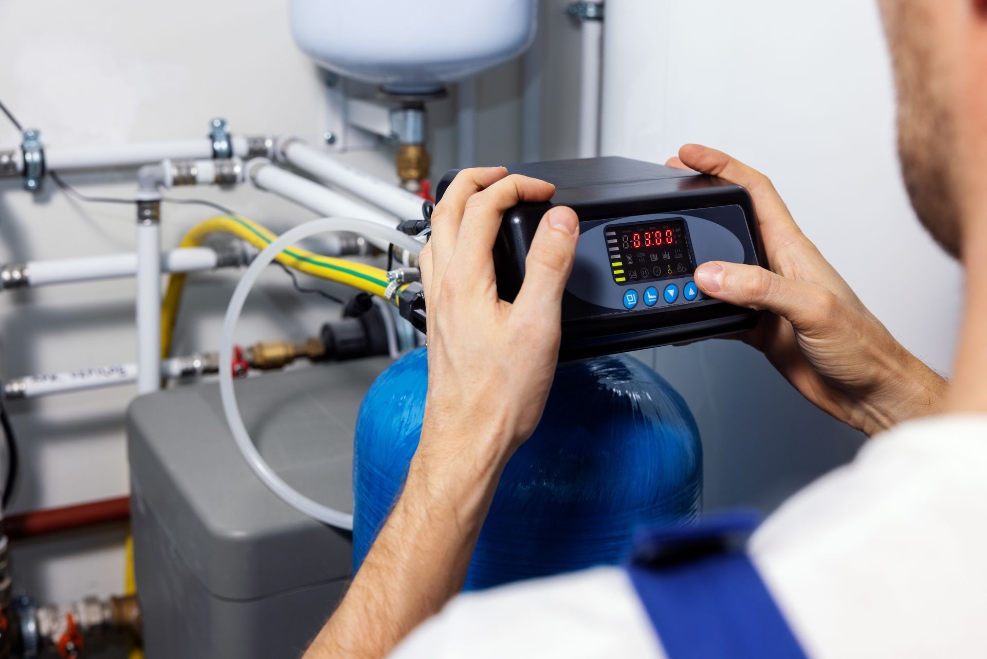 A man is holding a device in his hands while working on a water filter.
