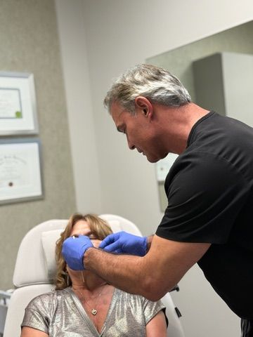 A person receiving a lip injection from a healthcare provider wearing blue gloves.
