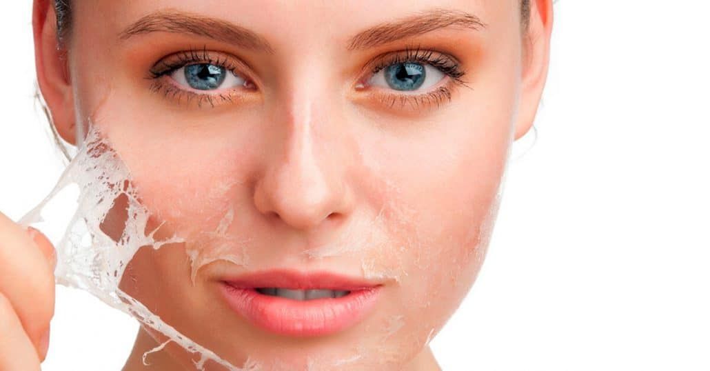 Woman peeling facial skin, looking at the camera, with a white background.