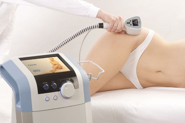 Medical device being used on a person's hip. A professional in white clothing holds the device.