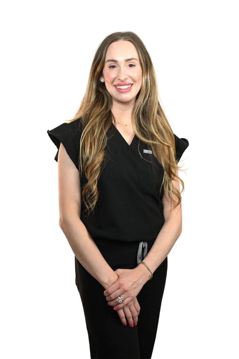 Woman in black scrubs, smiling, leaning against a white wall.