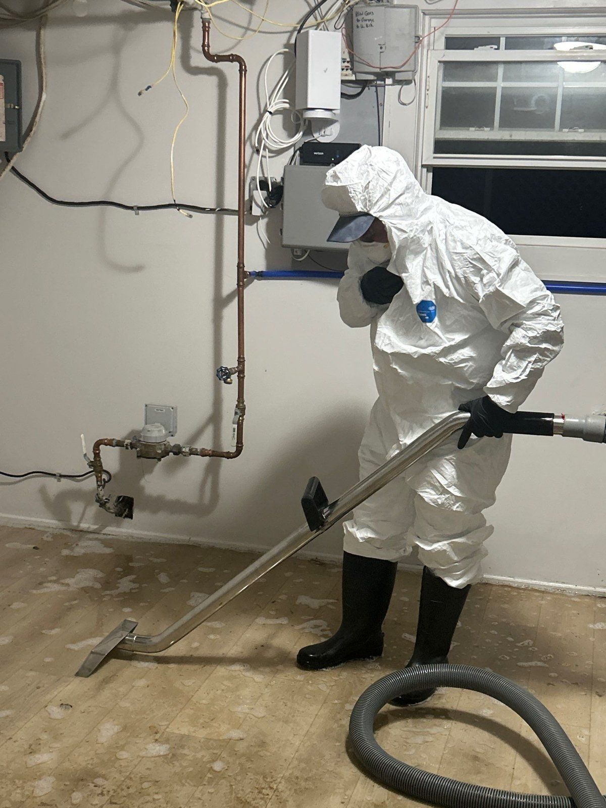 Technician in protective suit working by the sump pump in a flooded New Jersey basement