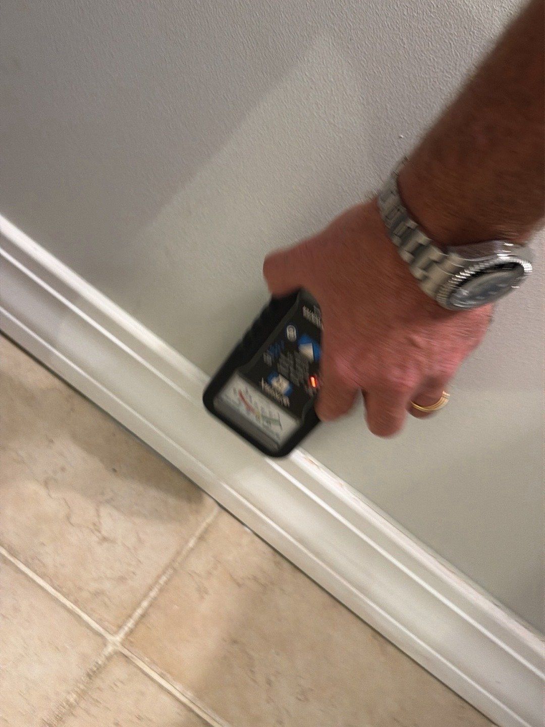 Technician checking a baseboard with a moisture meter during a water damage insurance claim in New Jersey