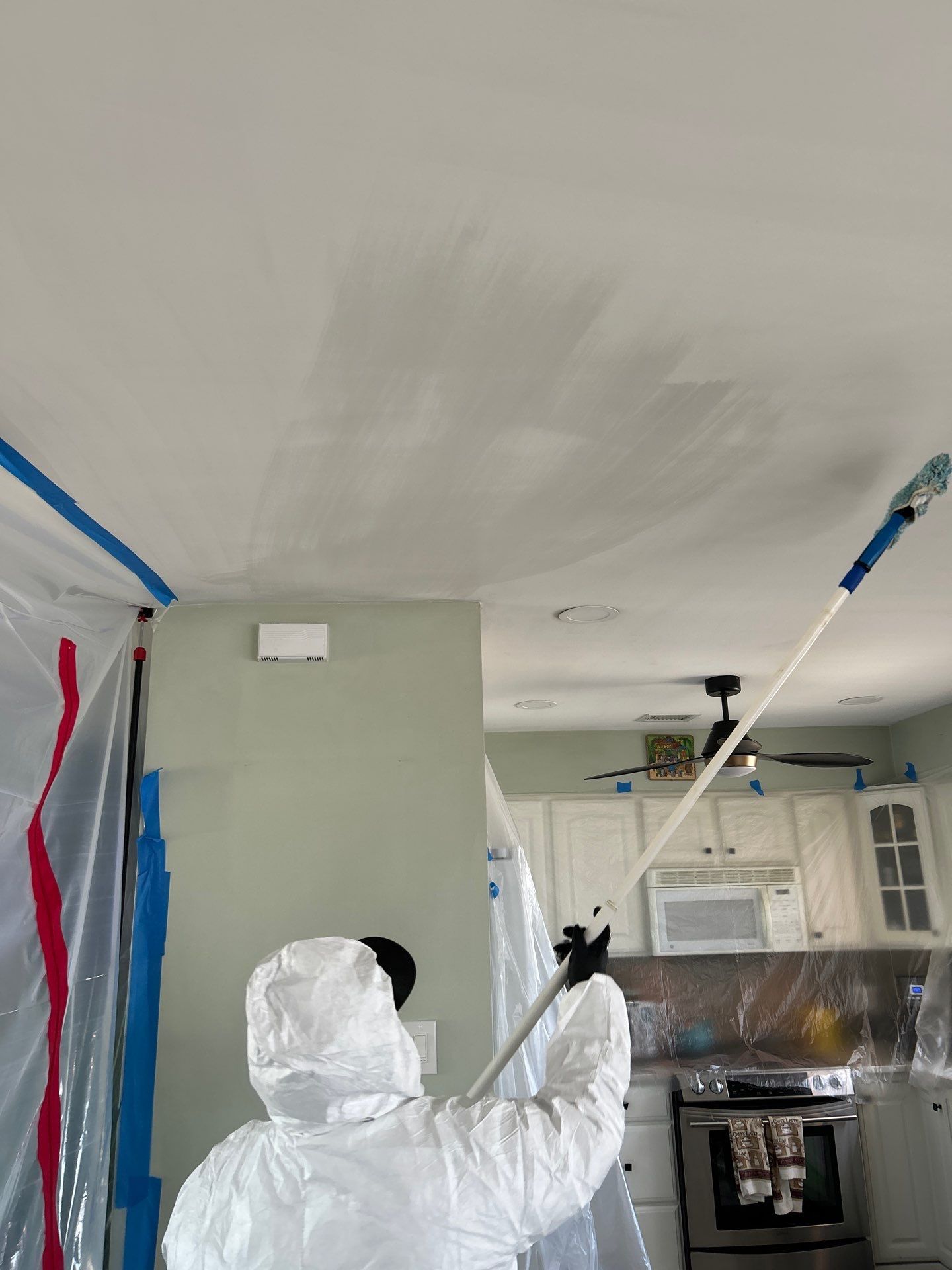 Technician removing soot from a ceiling during furnace puff-back cleanup