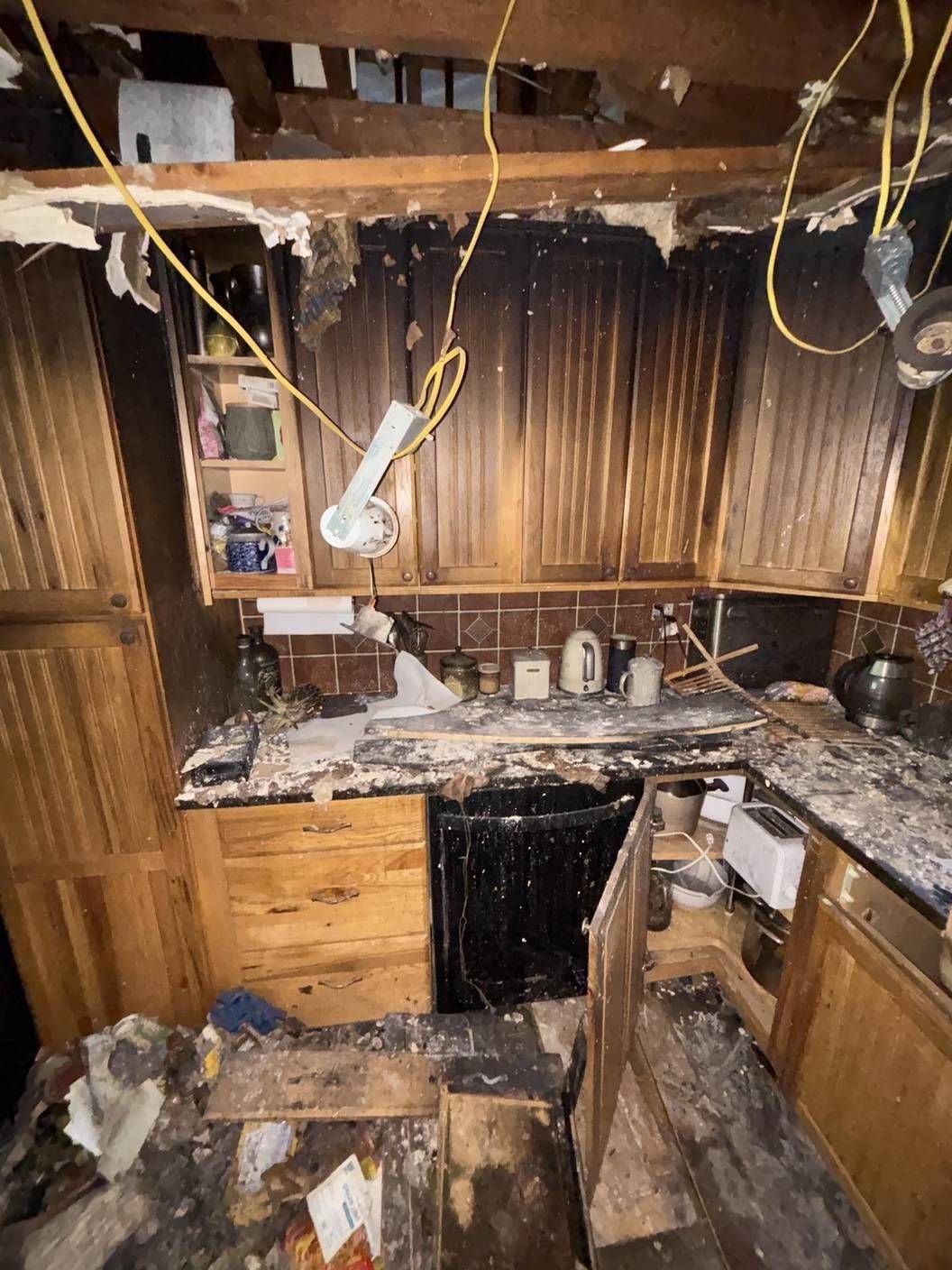 Fire-damaged kitchen with charred cabinets and debris before restoration