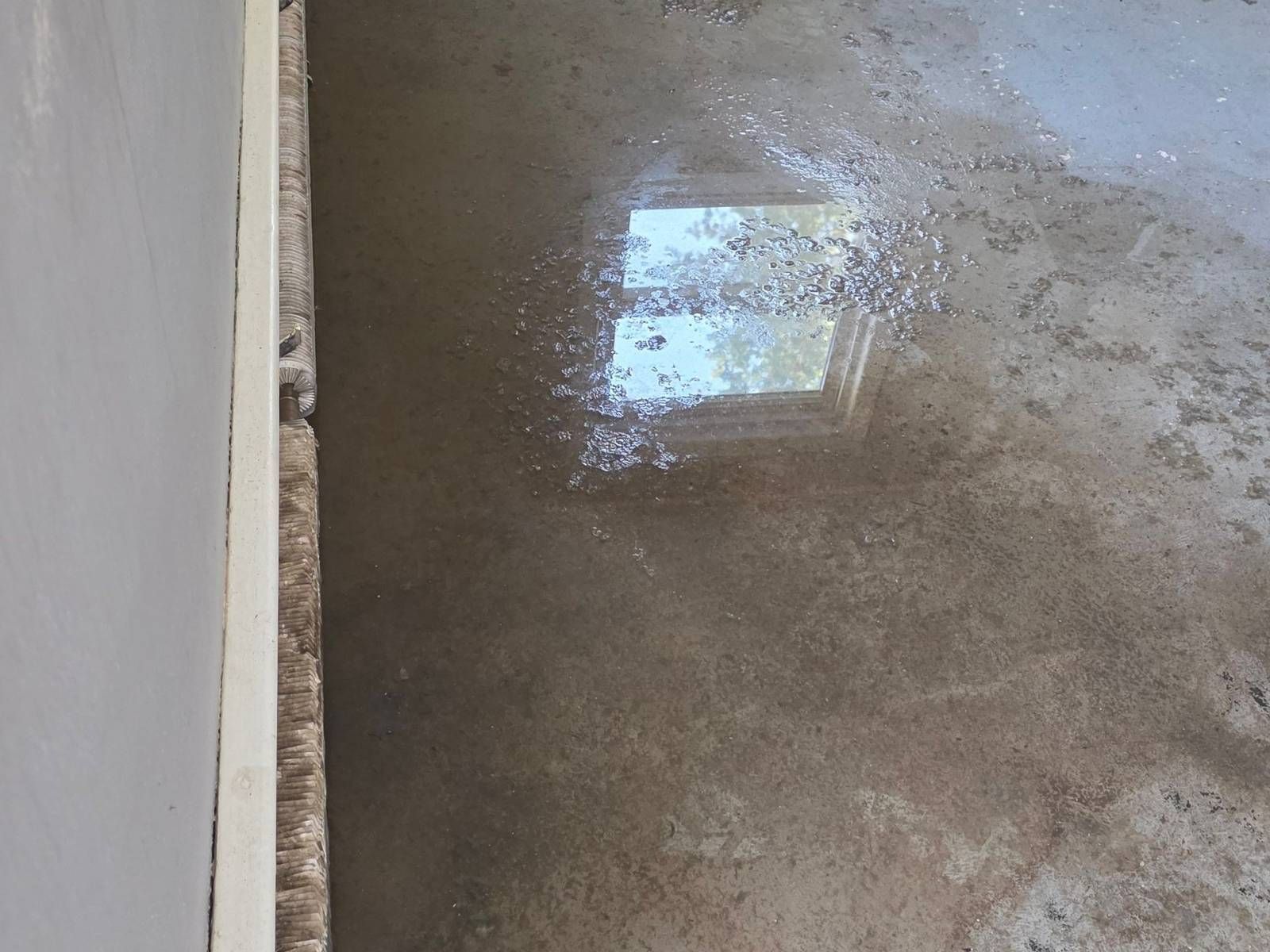 Standing water across a stripped basement floor after flooding