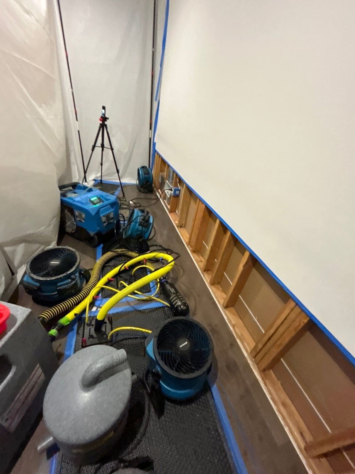 Flood-cut hallway walls with air movers and a dehumidifier drying after a burst pipe