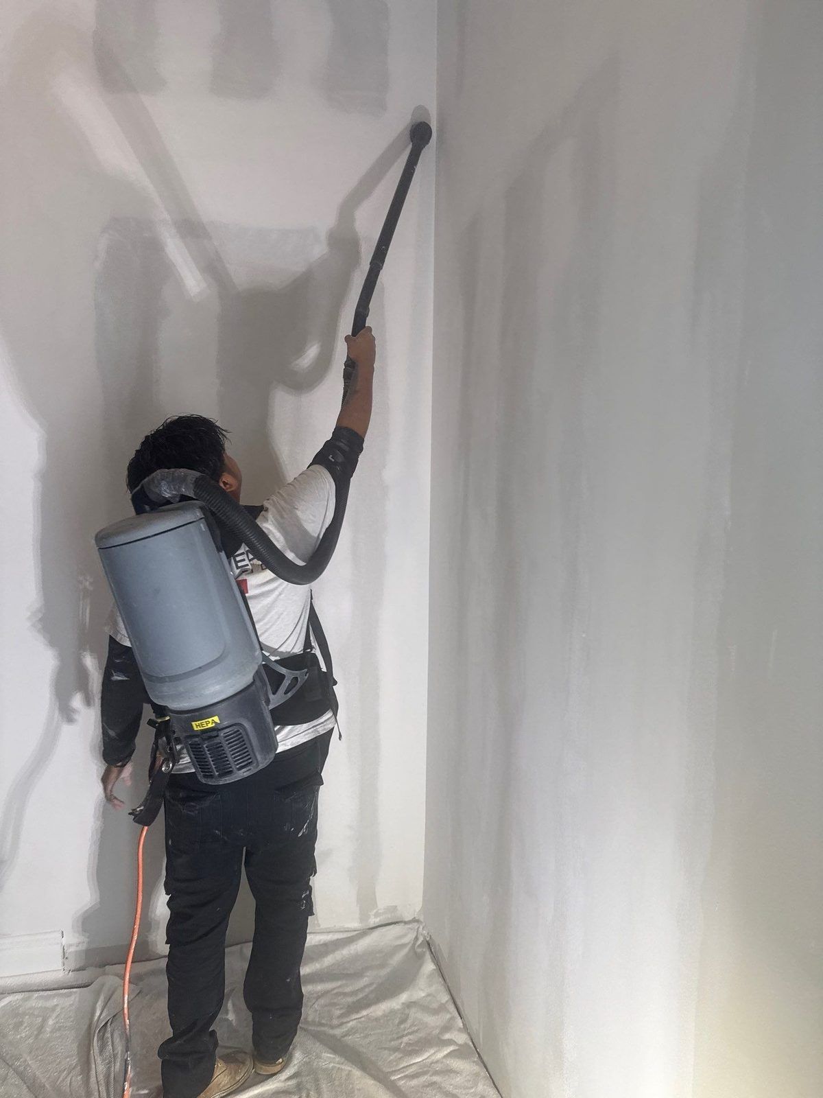 Technician spraying antimicrobial on walls inside plastic containment