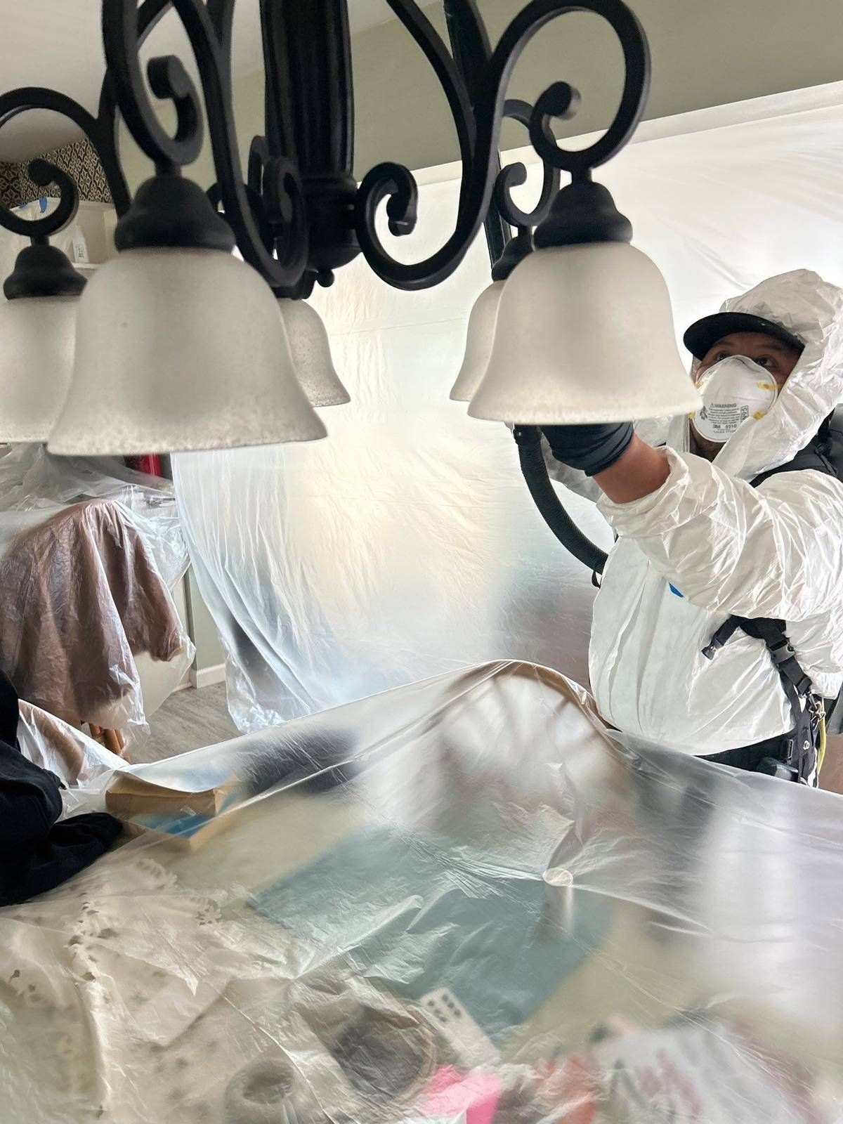 Technician cleaning soot from chandelier shades with a HEPA vacuum