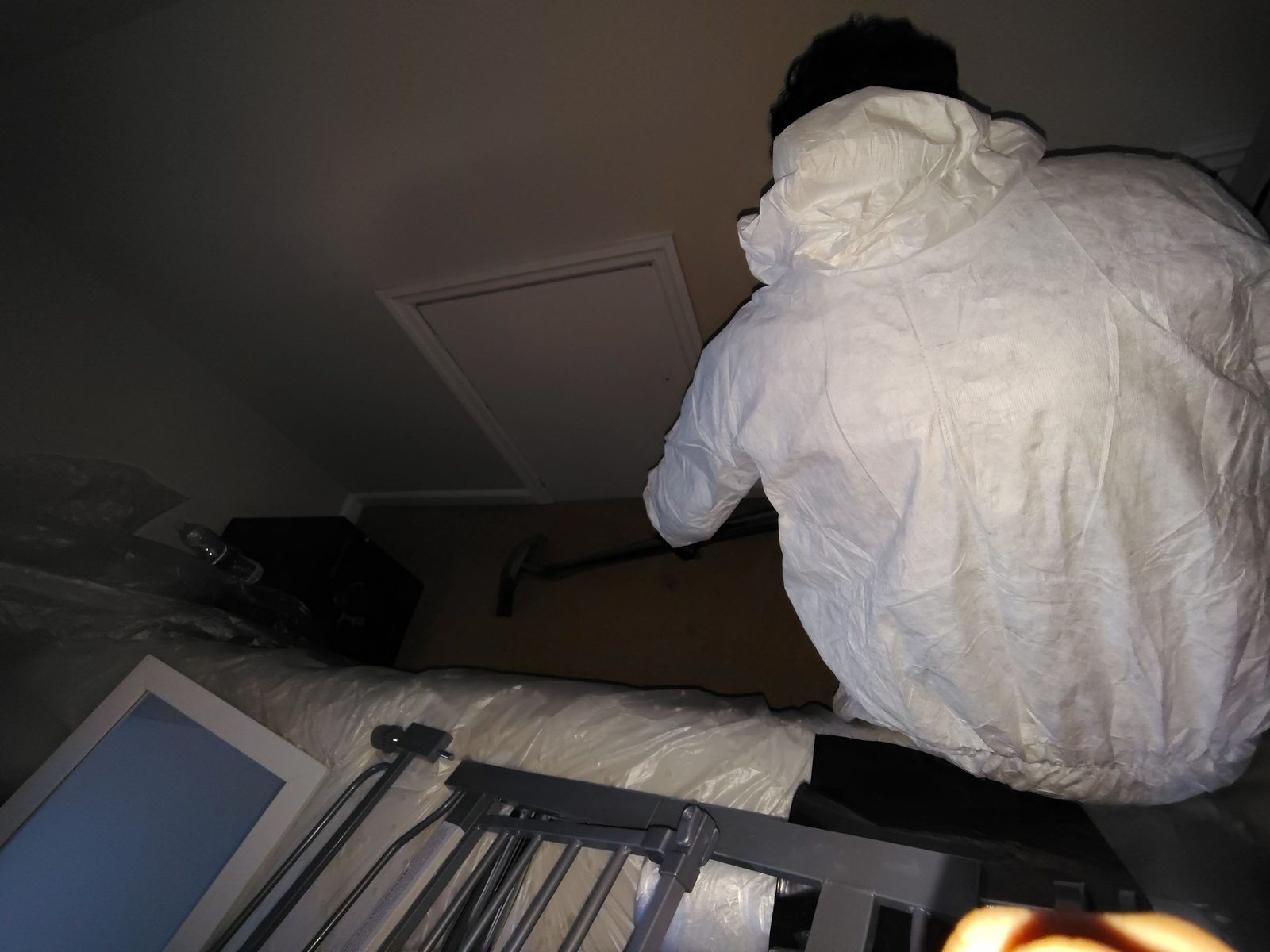 Technician in Tyvek cleaning soot from a ceiling inside containment