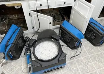 Dehumidifiers inside a cabinet with open doors, likely drying after water damage.