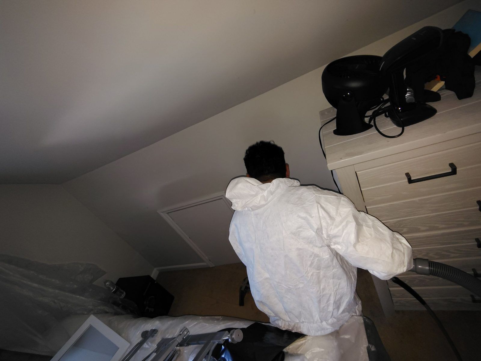 Technician in Tyvek cleaning smoke residue in a contained room