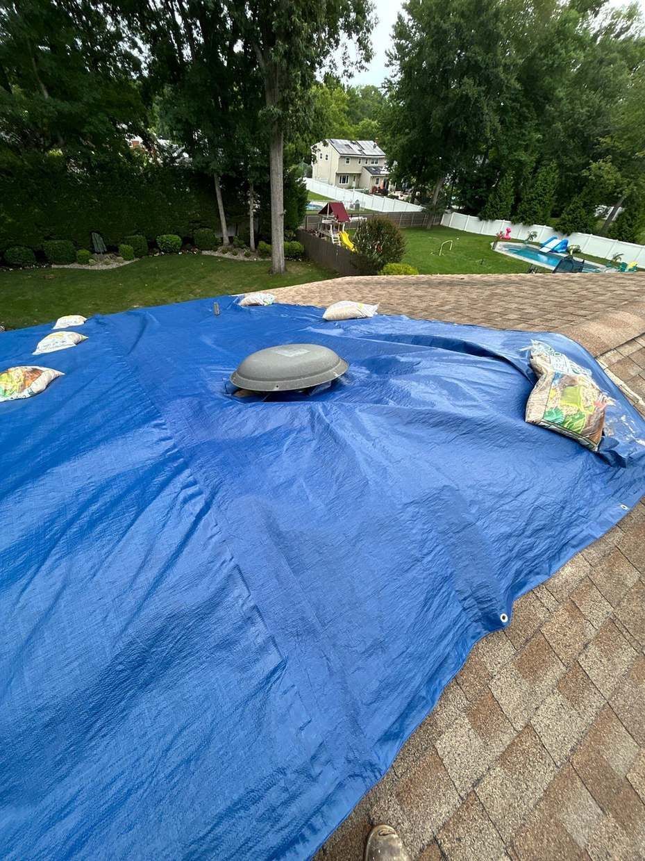 Blue tarp weighted with sandbags on a roof after storm damage