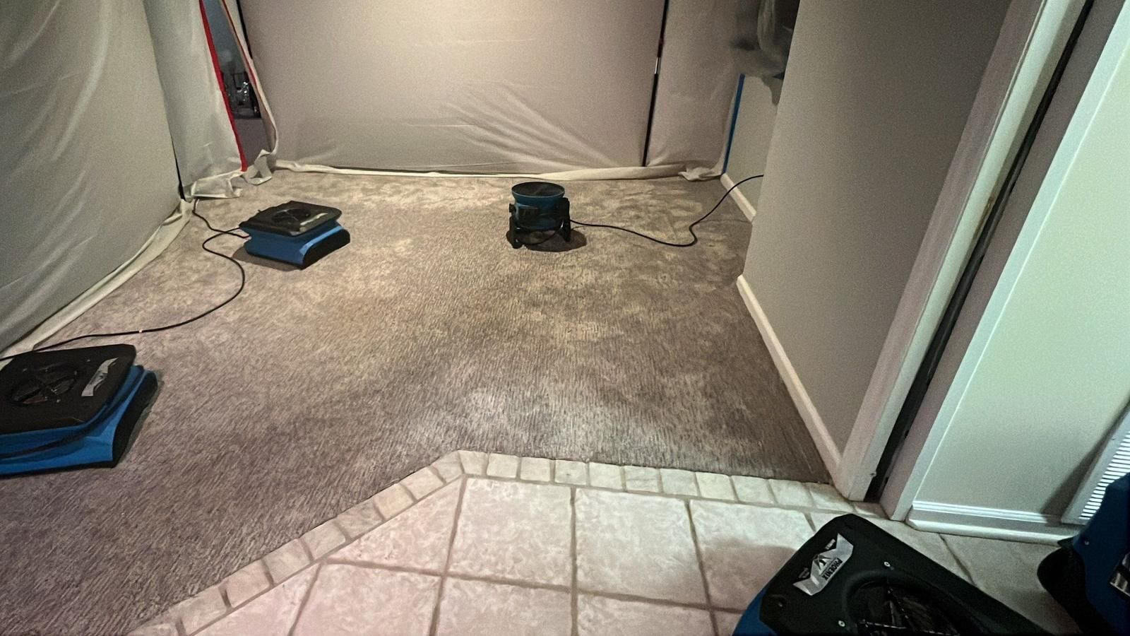 Room sealed in plastic containment with air movers drying the carpet