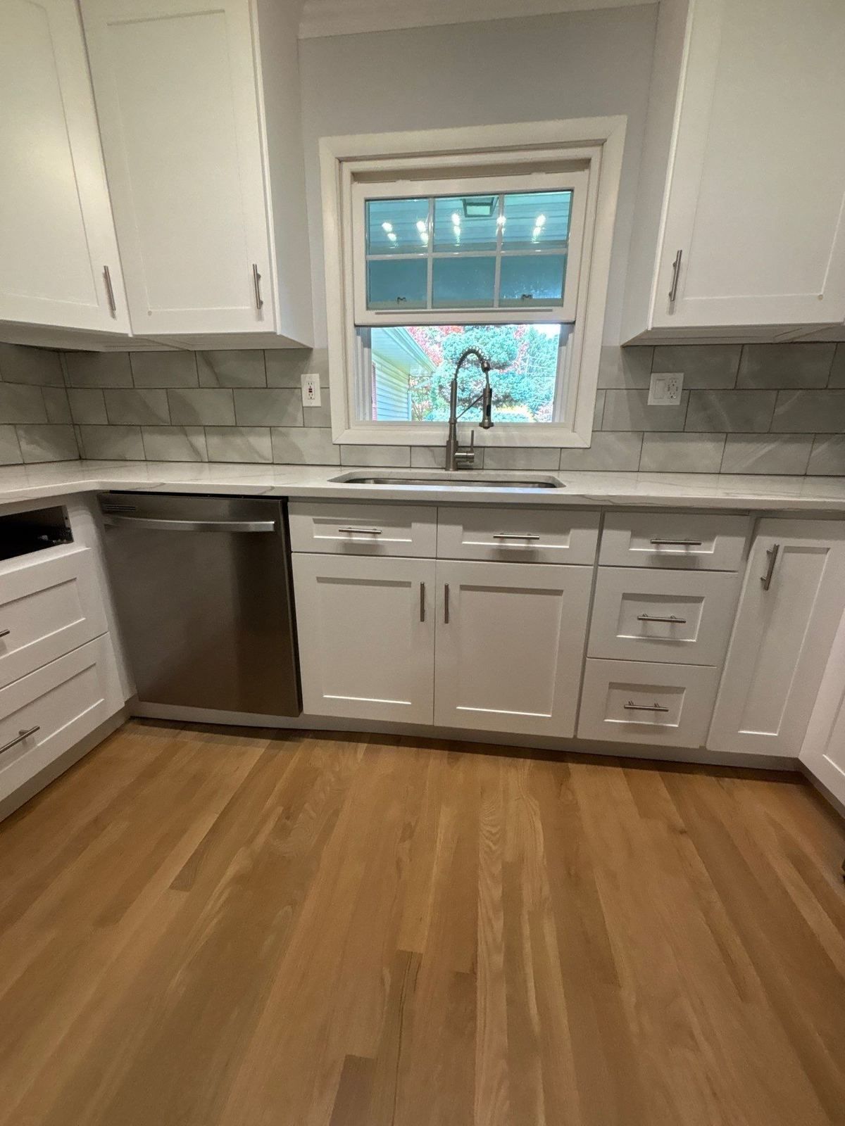 New white kitchen with quartz counters and tile backsplash after water damage