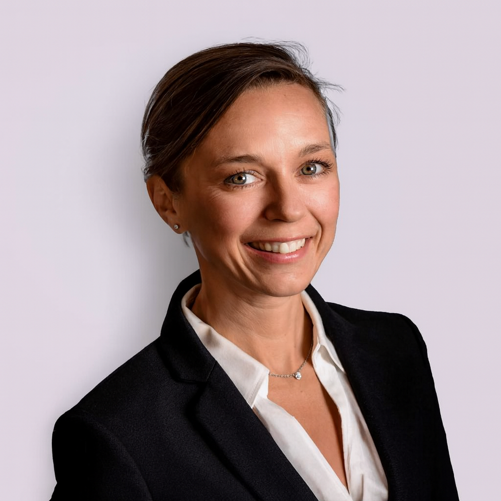 A woman in a suit and white shirt is smiling for the camera.