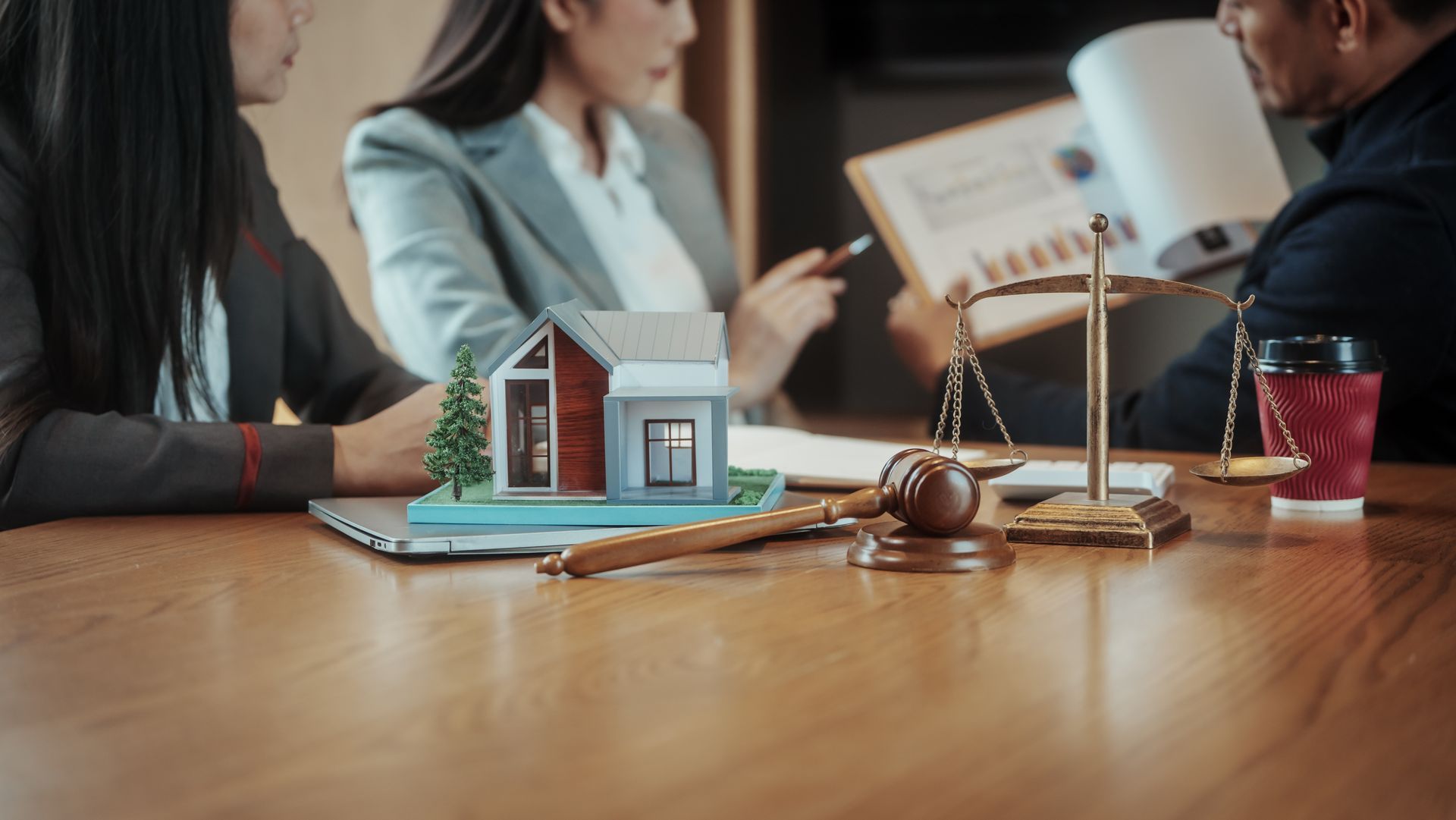 Business people discussing real estate documents with a house model and legal symbols